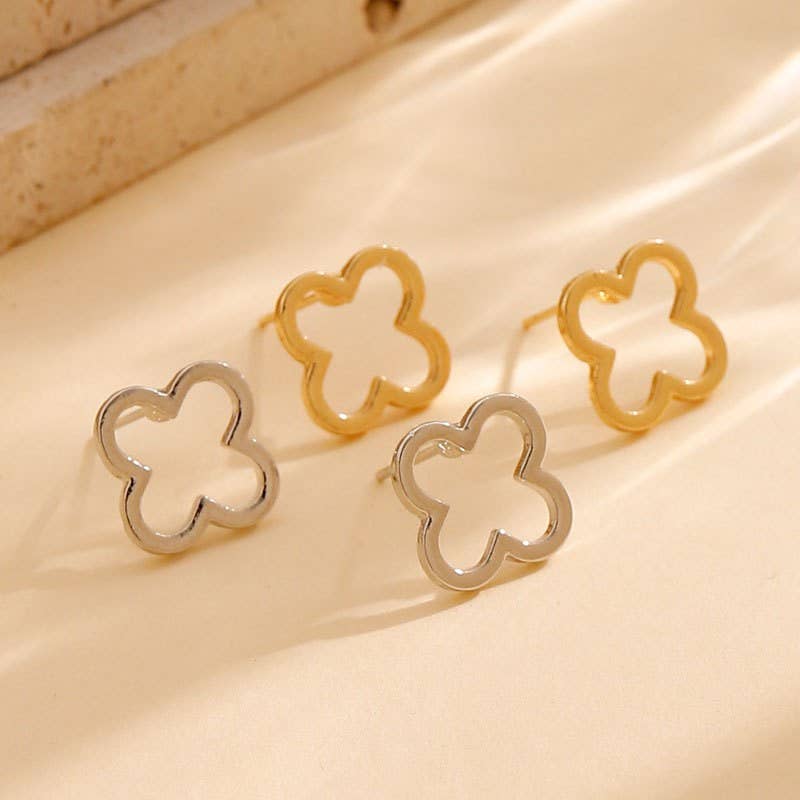 Gold clover-shaped earrings on a beige fabric background