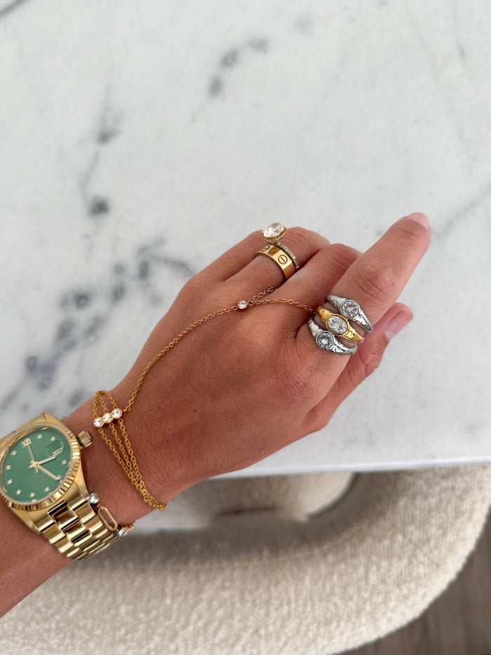 Hand wearing gold watch and bracelets with a marble background