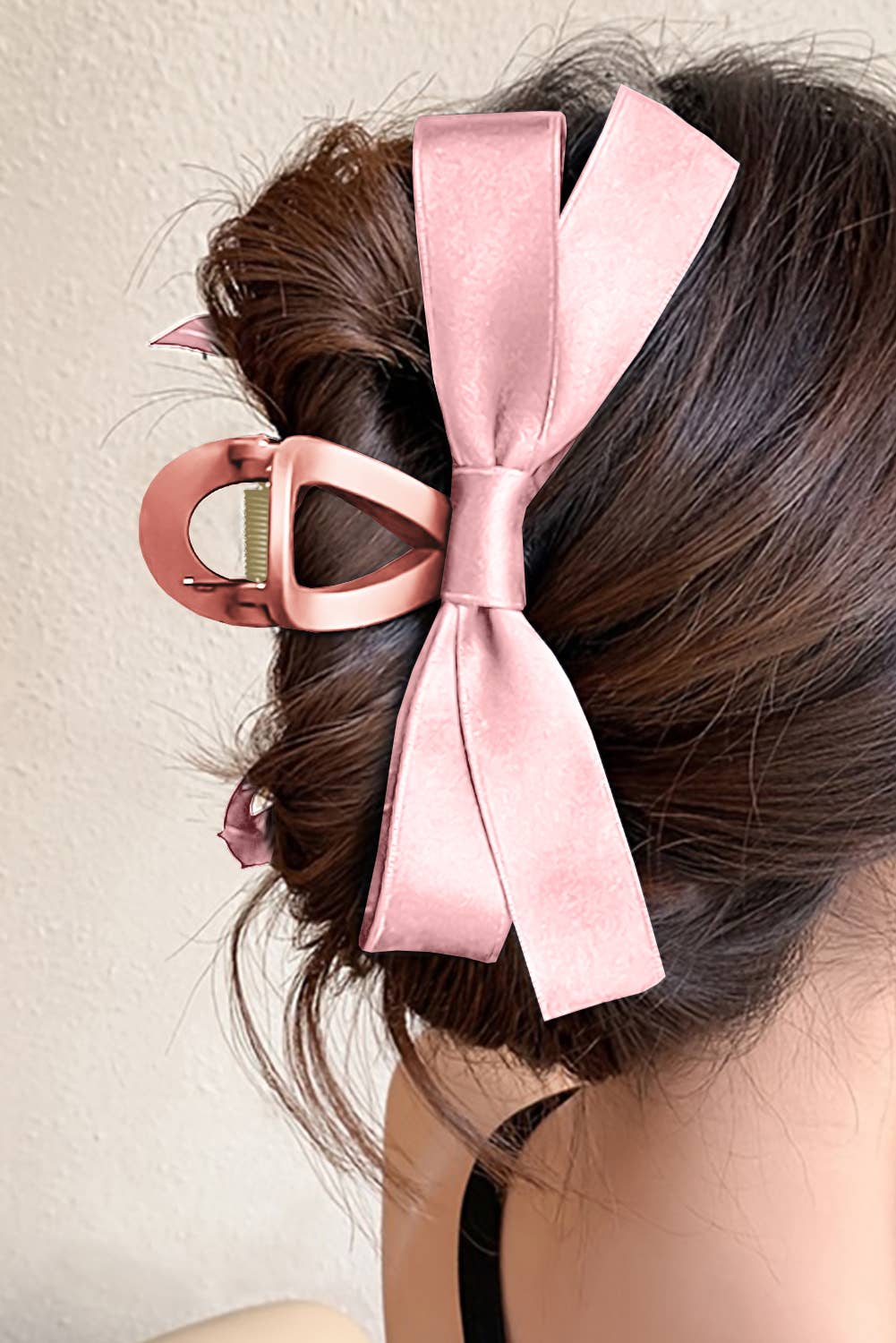 Pink hair bow accessory on a person's hair against a neutral background