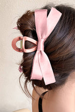 Pink hair bow accessory on a person's hair against a neutral background