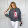 Woman wearing a gray sweatshirt with a Coca-Cola logo, holding a bottle of Coke.