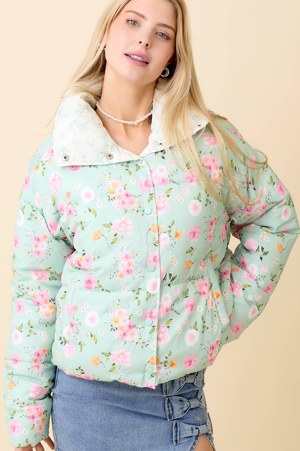 Woman wearing a floral patterned puffer jacket on a beige background