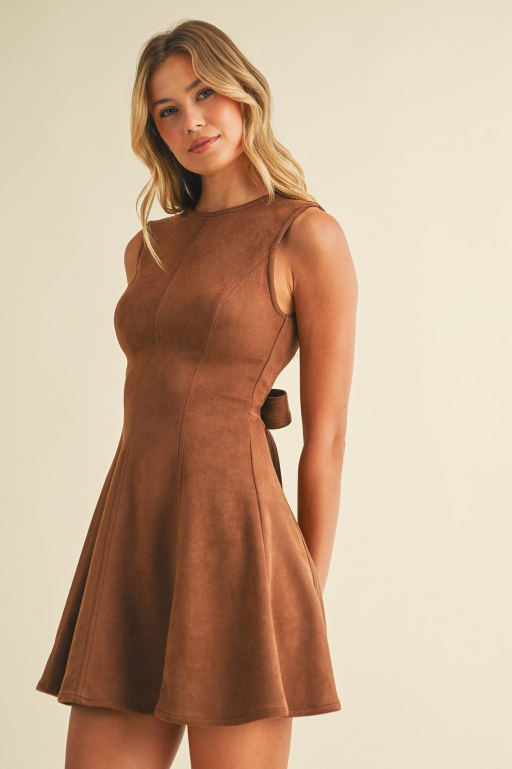 Woman wearing a brown dress against a beige background