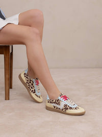 Person wearing leopard print sneakers with colorful accents on a neutral background