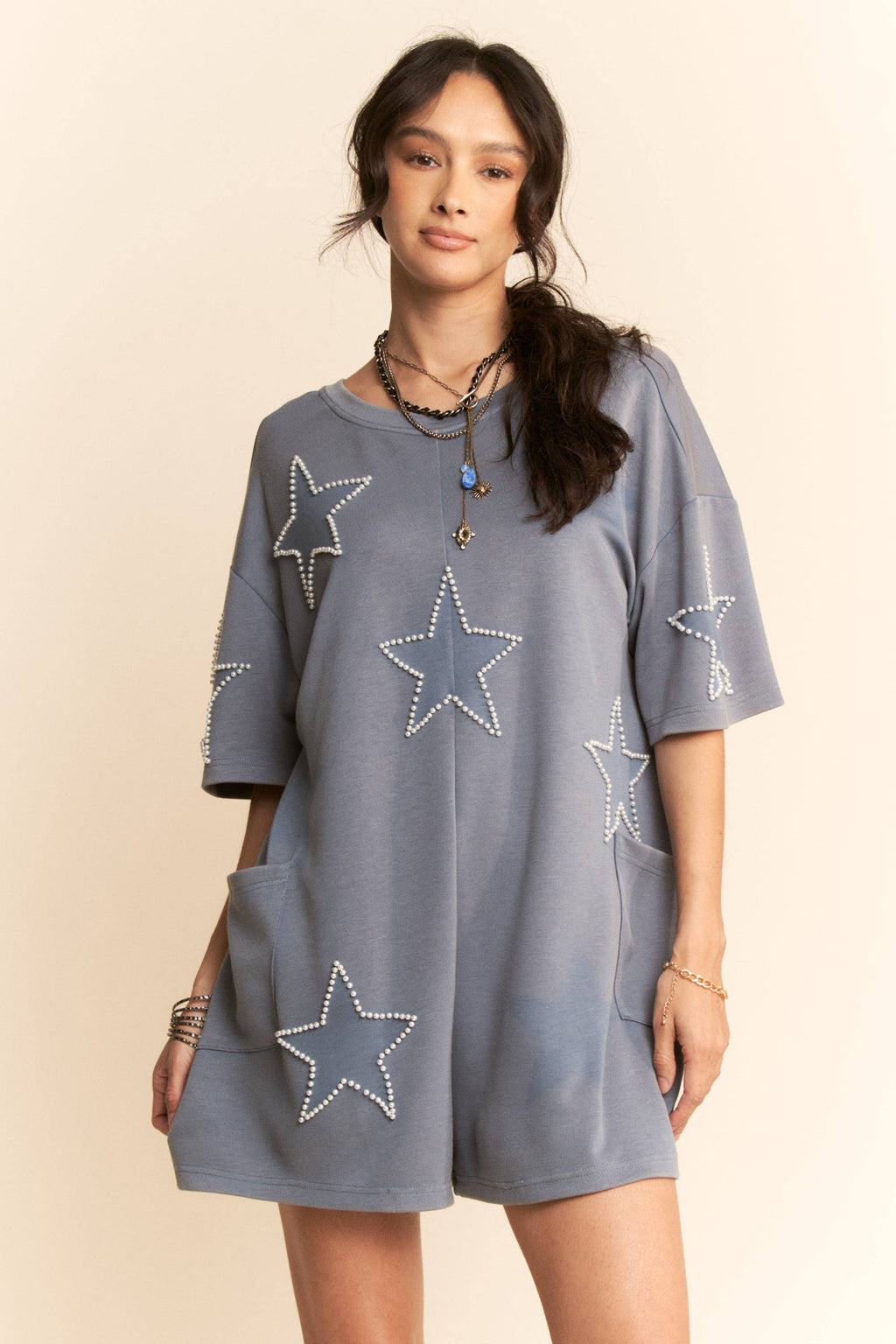 Woman wearing a gray dress with star patterns on a beige background