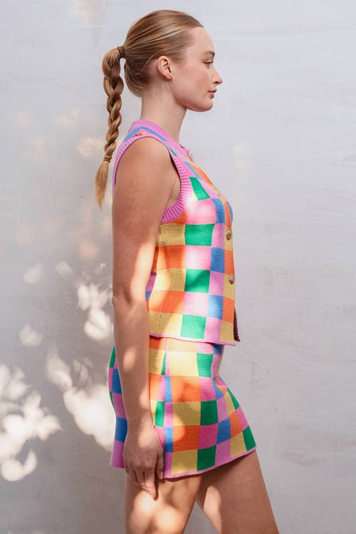 Woman wearing a colorful checkered outfit against a light background