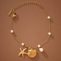 Gold bracelet with starfish, shell, and pearl charms on a brown background