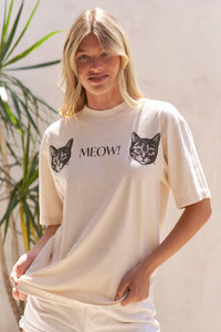 Woman wearing a cream t-shirt with cat graphics and 'MEOW!' text, standing against a light background.