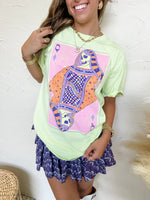 Woman wearing a light green t-shirt with a colorful graphic design on a white background