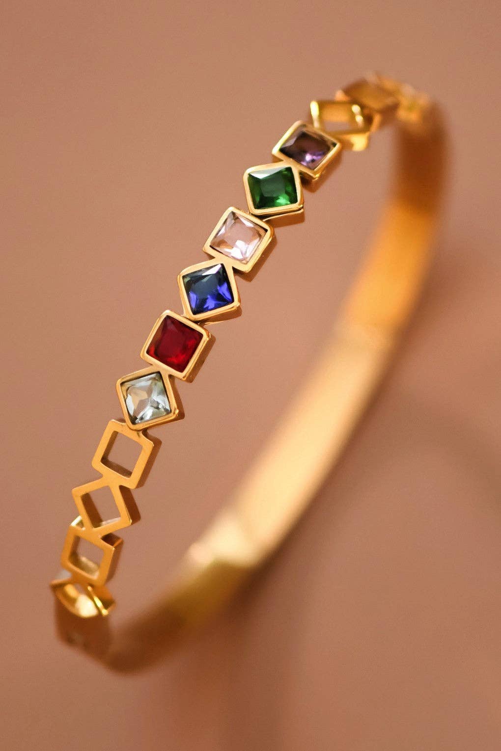 Gold bracelet with colorful gemstones on a brown background