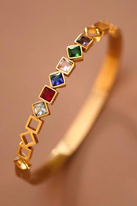 Gold bracelet with colorful gemstones on a brown background