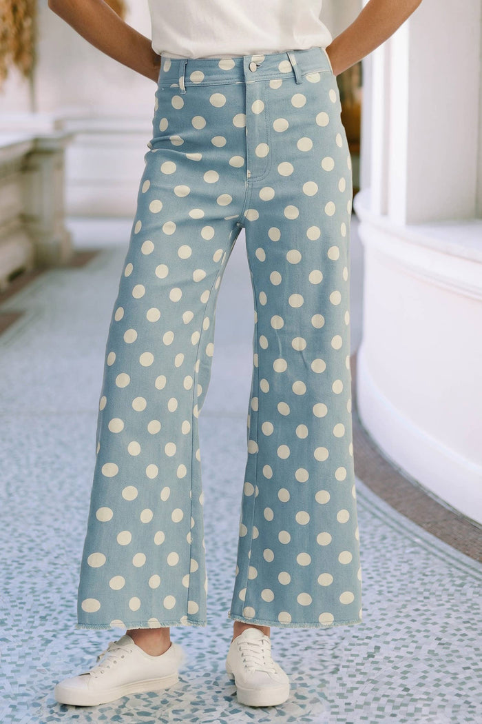Person wearing light blue jeans with white polka dots indoors.