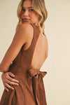 Woman wearing a brown dress with a beige background