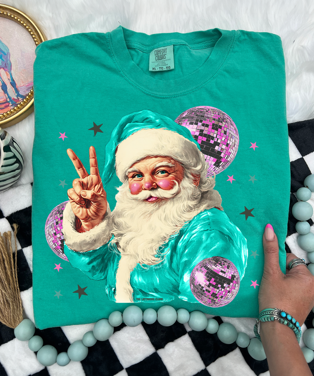 Teal t-shirt with a colorful Santa Claus design on a checkered surface.