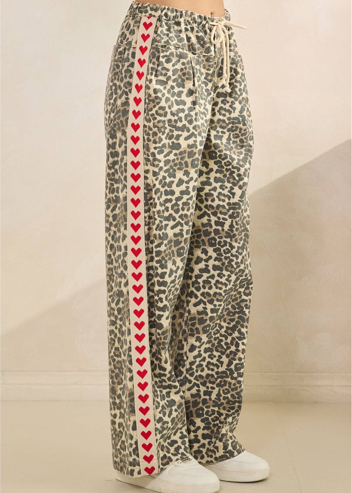 Leopard print pants with red heart pattern on a neutral background