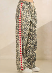Leopard print pants with red heart pattern on a neutral background