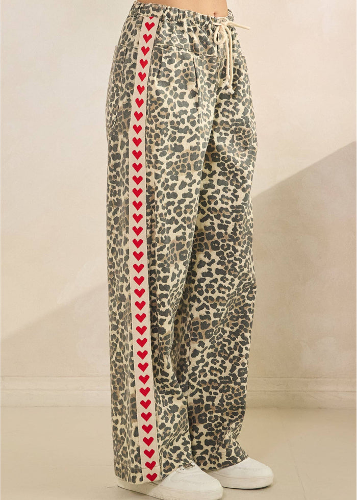 Leopard print pants with red heart pattern on a neutral background