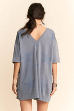 Woman wearing a gray tunic dress with a beige background