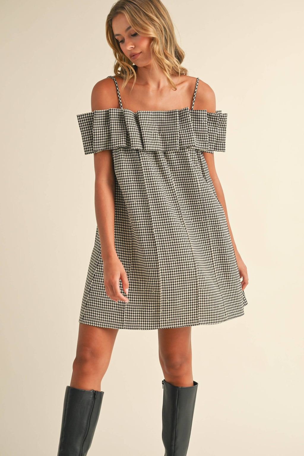 Woman wearing a checkered off-shoulder dress on a beige background