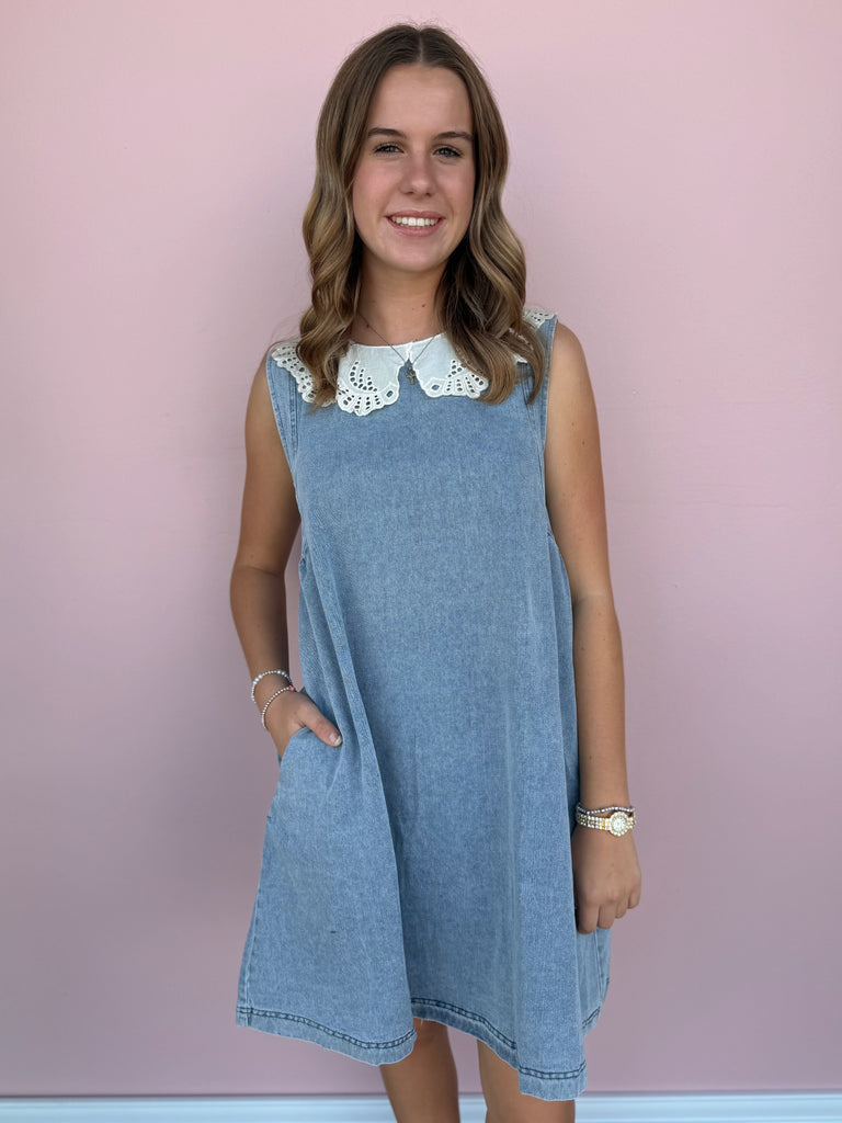 Woman wearing a blue dress with a white collar against a pink background