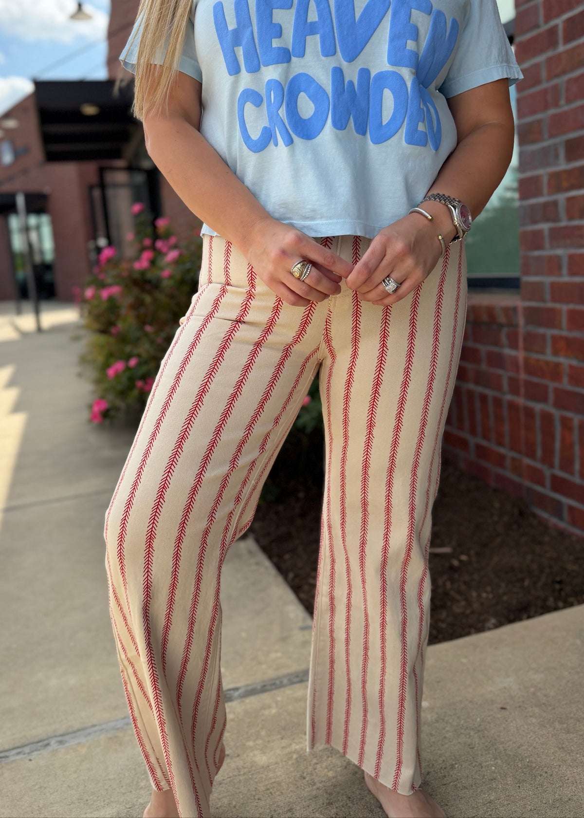Person wearing a white t-shirt with blue text and striped pants standing outdoors.