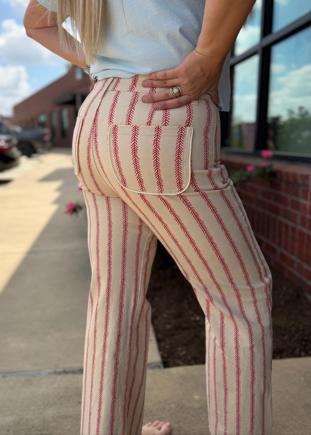 Person wearing a white t-shirt with blue text and striped pants standing outdoors.