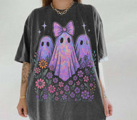 Person wearing a t-shirt with colorful ghost design and flowers on a plain background