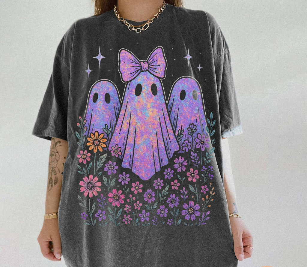 Person wearing a t-shirt with colorful ghost design and flowers on a plain background