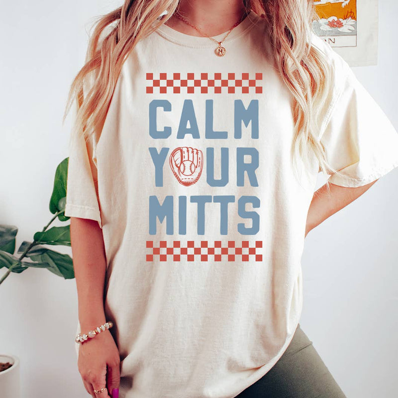 Person wearing a white t-shirt with 'CALM YOUR MITTS' text design.