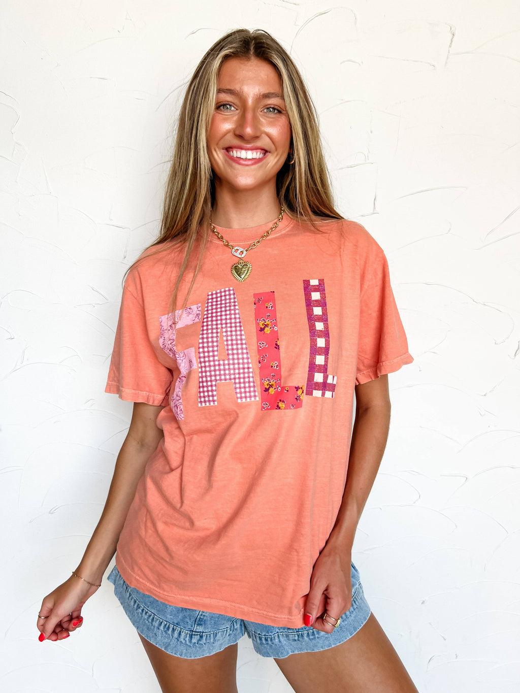 Woman wearing a coral t-shirt with a patterned design on a white background