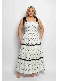 Woman wearing a white dress with black polka dots and a contrasting band on a white background