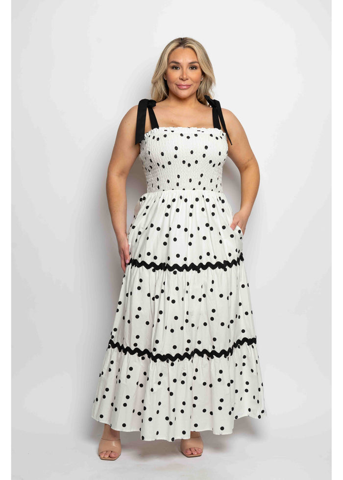 Woman wearing a white dress with black polka dots and a contrasting band on a white background