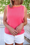 Person wearing a bright pink sleeveless top with colorful beads and white shorts outdoors.