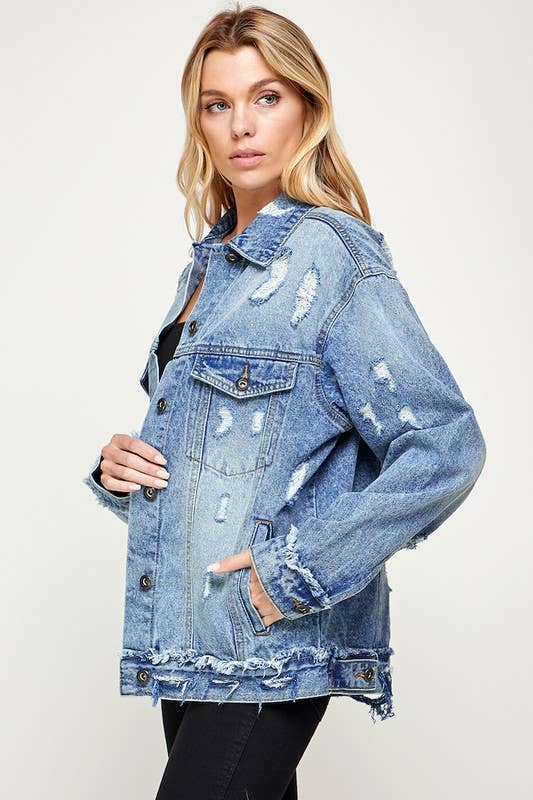 Woman wearing a distressed denim jacket on a plain background