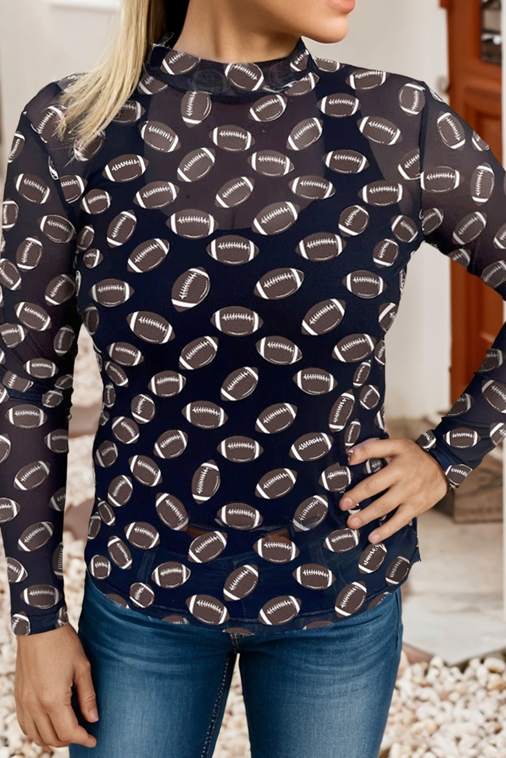 black long-sleeve top with football pattern worn by a person, standing against a neutral background.