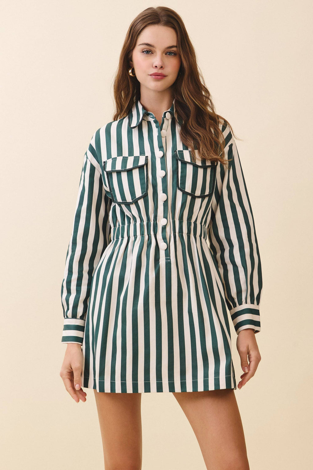 Woman wearing a green and white striped dress against a beige background