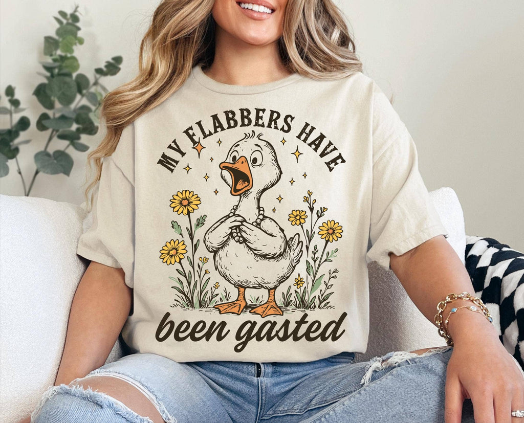 Person wearing a t-shirt with a graphic of a duck and text, sitting on a couch.