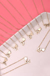 Gold necklaces with letter pendants on a pink surface