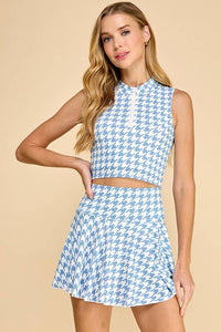 Woman wearing a blue and white houndstooth patterned two-piece outfit on a beige background