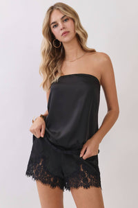 Woman wearing a black strapless top and lace shorts on a white background