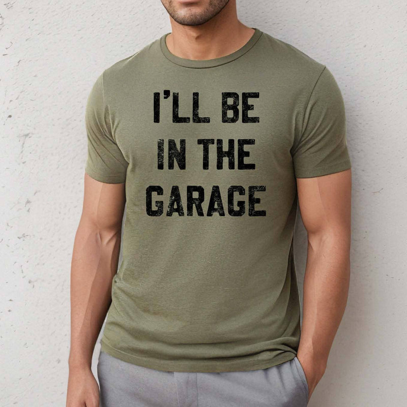 Person wearing a green t-shirt with 'I'll be in the garage' text against a light gray background