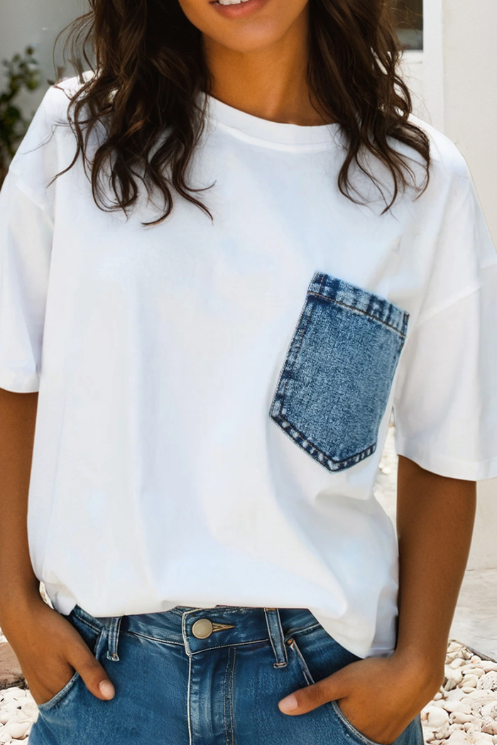 White t-shirt with denim pocket design worn by a person outdoors.