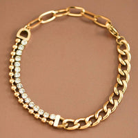 Gold chain necklace with embedded crystals on a brown background