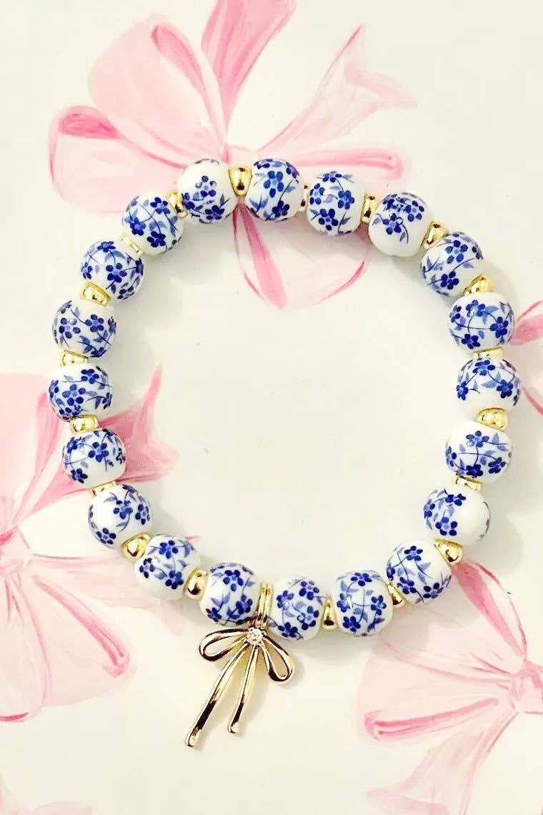 Beaded bracelet with blue floral pattern and gold accents on a pink floral background