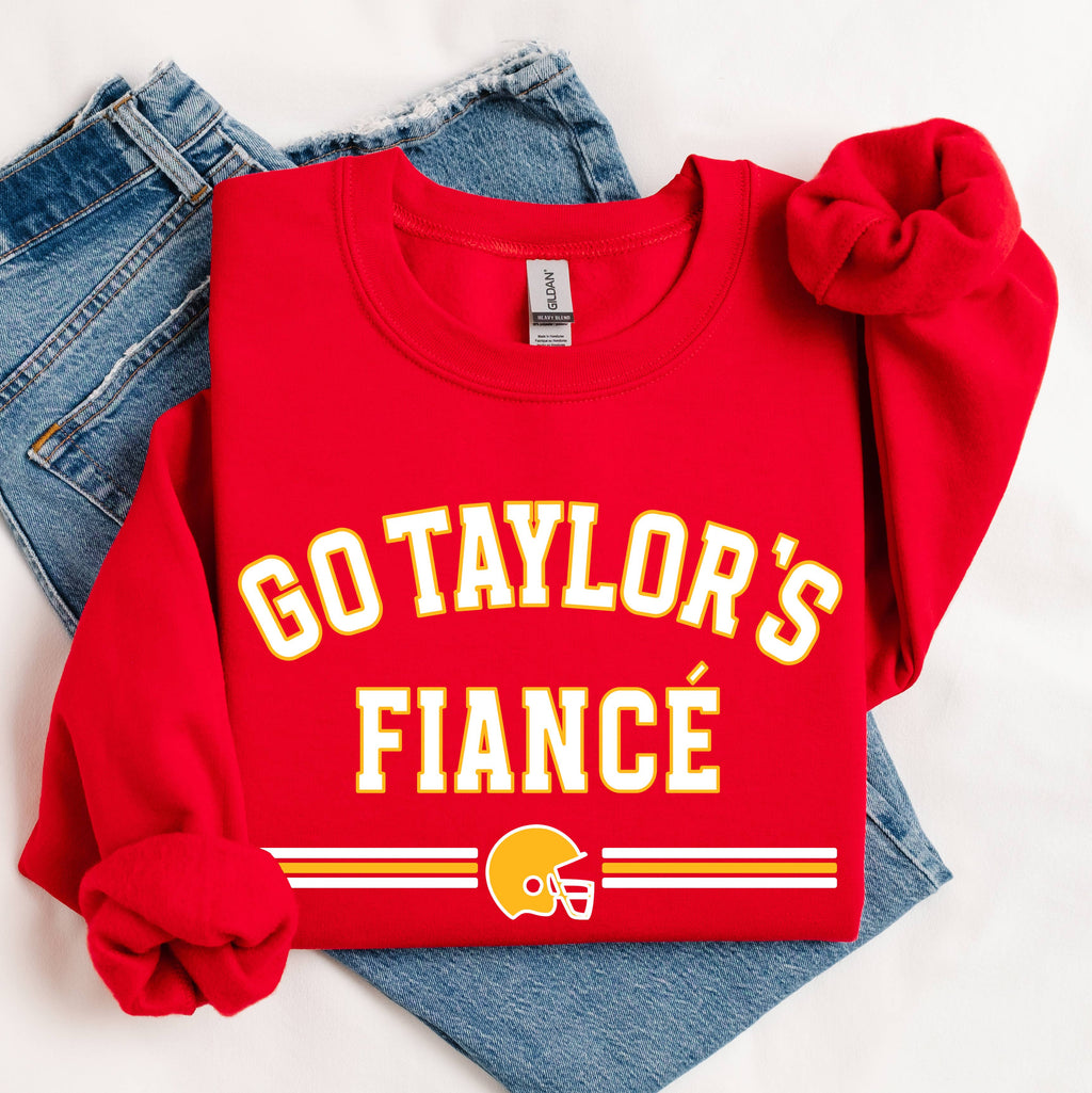 Red sweatshirt with 'GO TAYLOR'S FIANCÙ' text and football helmet graphic on a white background.