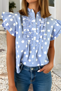 Woman wearing a blue and white polka dot blouse with ruffled sleeves.