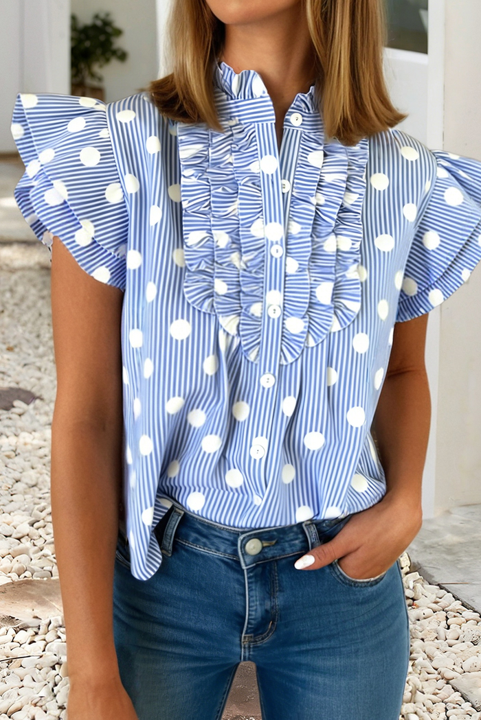 Woman wearing a blue and white polka dot blouse with ruffled sleeves.
