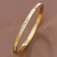 Gold bracelet with white stones on a brown background
