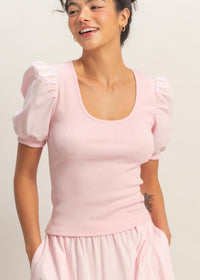 Woman wearing a pink dress with puffed sleeves on a plain background